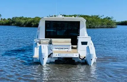  Yacht Photos Pics Aquila 36 Sport 2023 boat on calm water with lush greenery in the background.