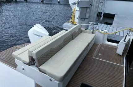  Yacht Photos Pics 2023 Aquila 36 Sport boat with beige seating and wooden deck by the water.