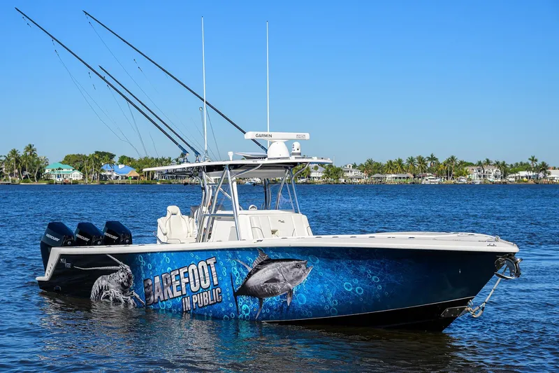 Barefoot In Public Yacht Photos Pics 2023 SeaVee 370Z boat with fishing rods, vibrant graphics, and Mercury engines on a sunny day.