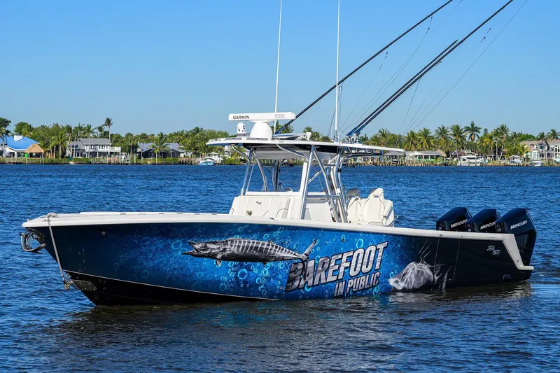 Barefoot In Public Yacht Photos Pics 2023 SeaVee 370Z boat on water, vibrant graphics, palm trees in background.