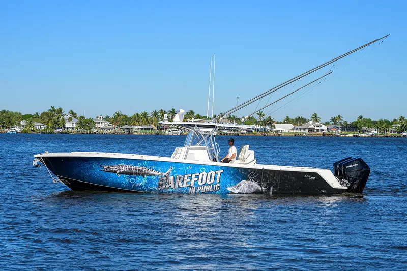 Barefoot In Public Yacht Photos Pics 2023 SeaVee 370Z boat on water, vibrant graphics, clear blue sky, coastal background.