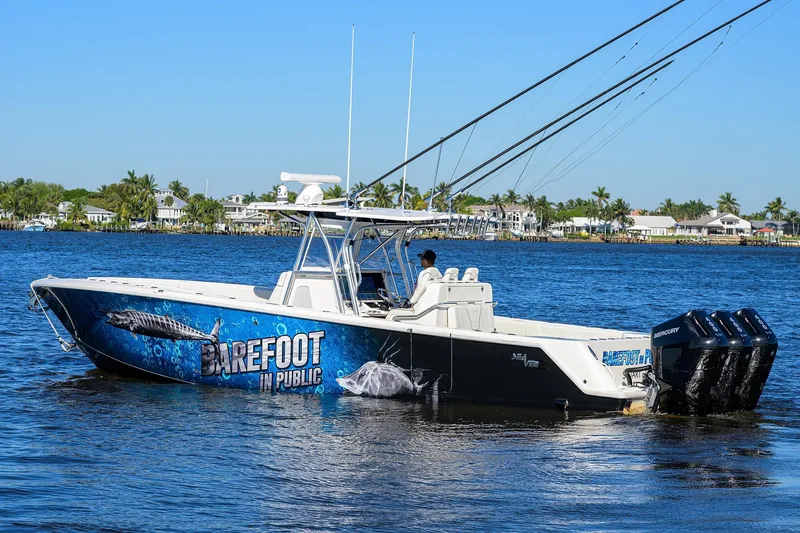 Barefoot In Public Yacht Photos Pics 2023 SeaVee 370Z boat on water, vibrant graphics, palm trees in background.