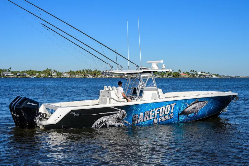 Barefoot In Public Yacht Photos Pics 2023 SeaVee 370Z boat on water, vibrant graphics, fishing rods, clear blue sky.