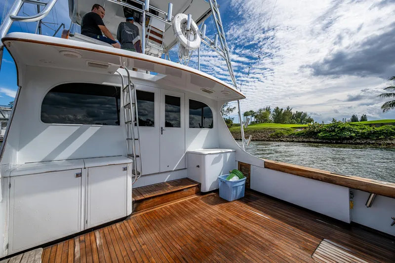 Able Hand Yacht Photos Pics 1978 Graves 51 boat with wooden deck, docked by a scenic riverbank under a cloudy sky.
