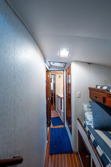 Able Hand Yacht Photos Pics Narrow hallway inside a 1978 Graves 51 boat, featuring wooden flooring and blue carpet.