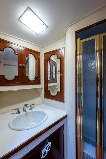 Able Hand Yacht Photos Pics Vintage 1978 Graves 51 bathroom with wooden cabinets and a glass shower door.