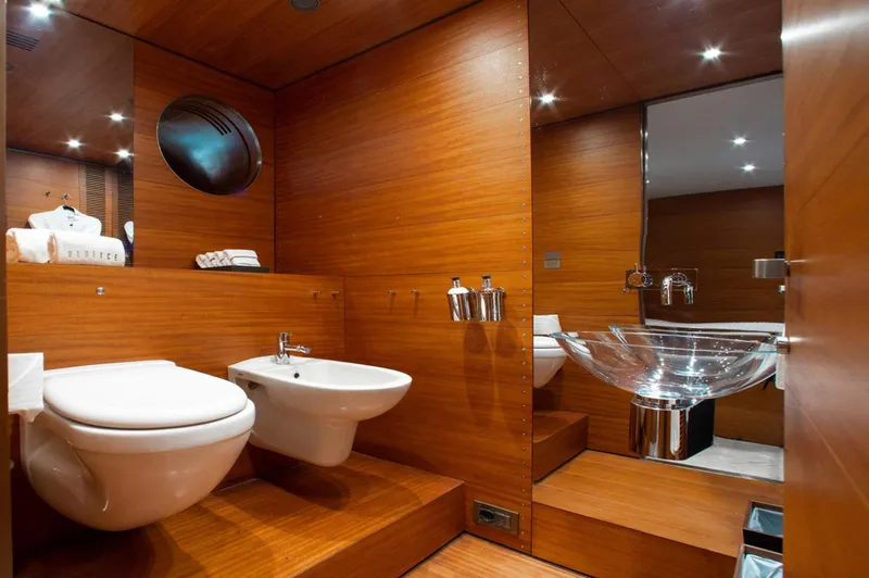 Matrix Yacht Photos Pics Luxurious wooden bathroom in 1999 Baglietto 41M yacht with modern fixtures and glass sink.