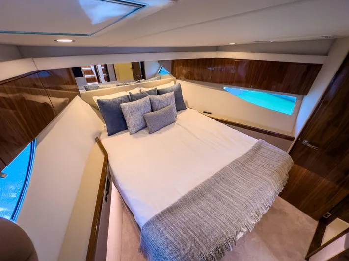  Yacht Photos Pics Luxurious bedroom interior of 2024 Riviera 465 SUV yacht with elegant bedding and wood accents.