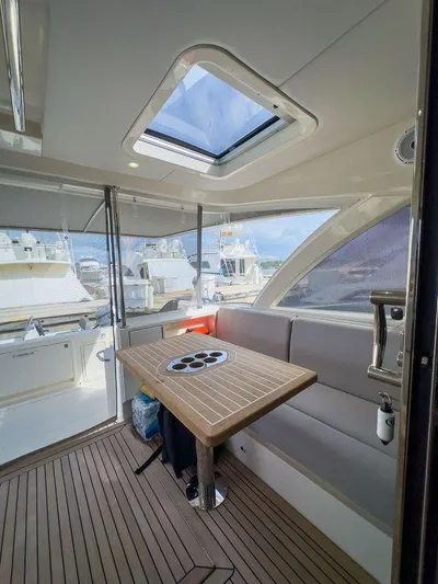  Yacht Photos Pics 2024 Riviera 465 SUV interior with skylight, wooden table, and seating area.