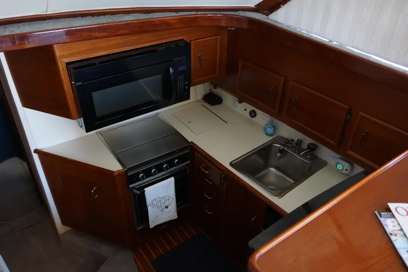 The Dog House Yacht Photos Pics 1988 Ocean Yachts Super Sport kitchen with wood cabinetry, microwave, stove, and sink.