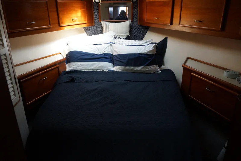 The Dog House Yacht Photos Pics Cozy bedroom in 1988 Ocean Yachts Super Sport with wooden cabinets and striped bedding.