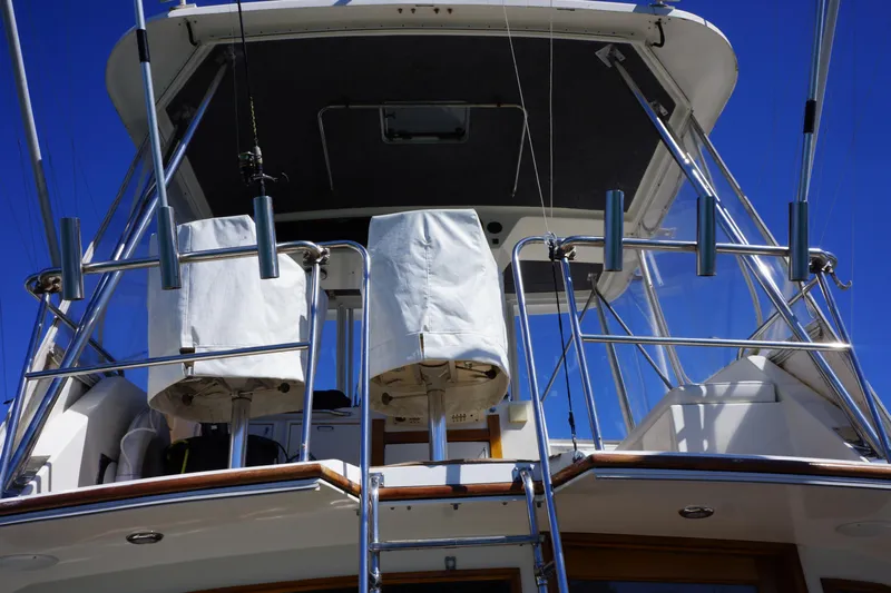 The Dog House Yacht Photos Pics 1988 Ocean Yachts Super Sport boat deck with covered seats and metal railings under clear blue sky.
