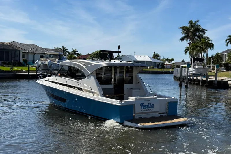  Yacht Photos Pics 2021 Riviera 395 SUV cruising in a sunny waterfront neighborhood.
