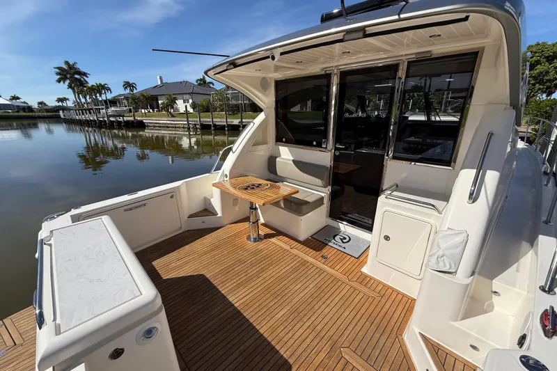  Yacht Photos Pics 2021 Riviera 395 SUV yacht with teak deck, docked by waterfront homes.