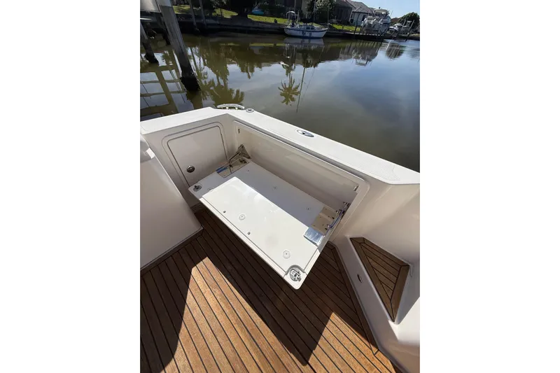 Yacht Photos Pics 2021 Riviera 395 SUV boat deck with open storage compartment, docked by calm waters.