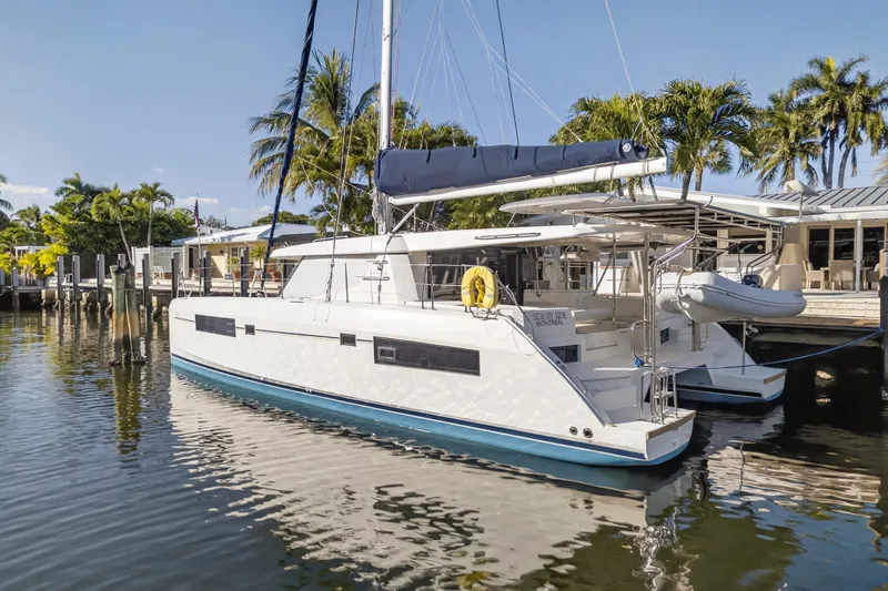  Yacht Photos Pics 2019 Leopard 45 catamaran docked by palm trees and waterfront homes.