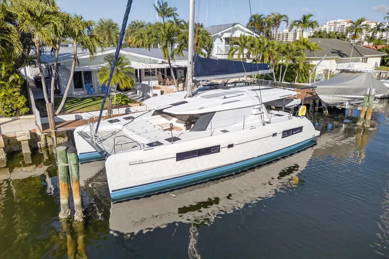  Yacht Photos Pics 2019 Leopard 45 catamaran docked by a tropical waterfront home.