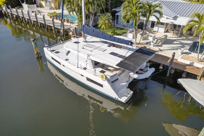  Yacht Photos Pics 2019 Leopard 45 catamaran docked by a waterfront home with palm trees.