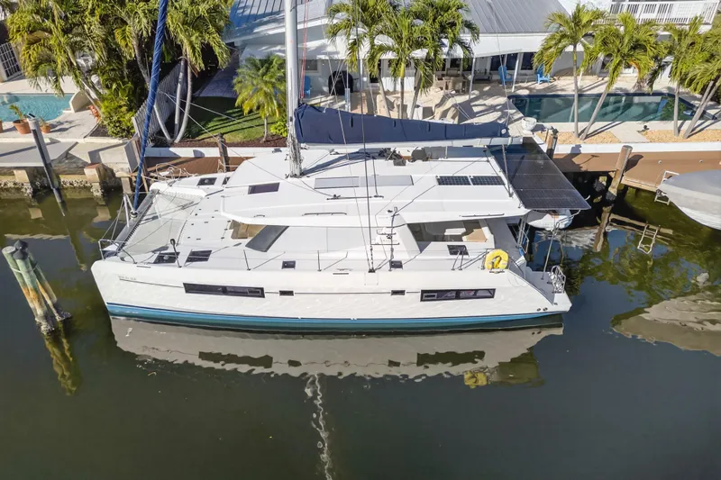  Yacht Photos Pics 2019 Leopard 45 catamaran docked by a tropical waterfront home.