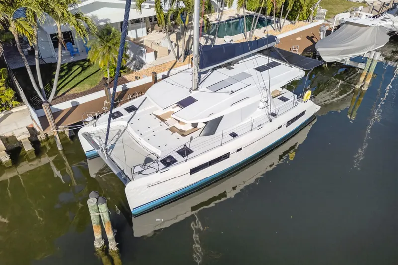  Yacht Photos Pics 2019 Leopard 45 catamaran docked by a waterfront home with lush greenery.