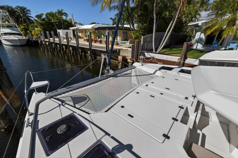  Yacht Photos Pics 2019 Leopard 45 catamaran docked by a tropical waterfront home.
