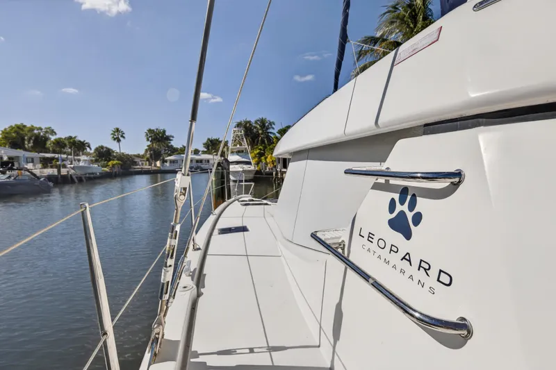  Yacht Photos Pics 2019 Leopard 45 catamaran docked in a sunny marina, showcasing sleek design and branding.
