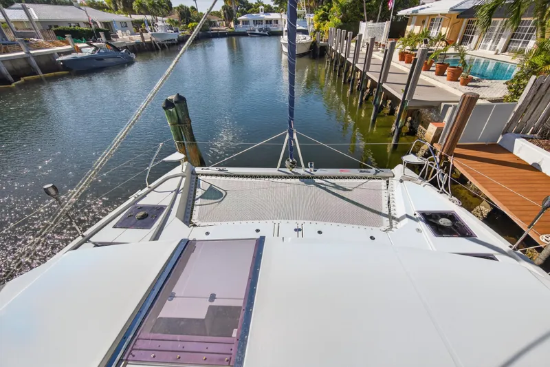  Yacht Photos Pics 2019 Leopard 45 catamaran docked in a sunny residential canal setting.