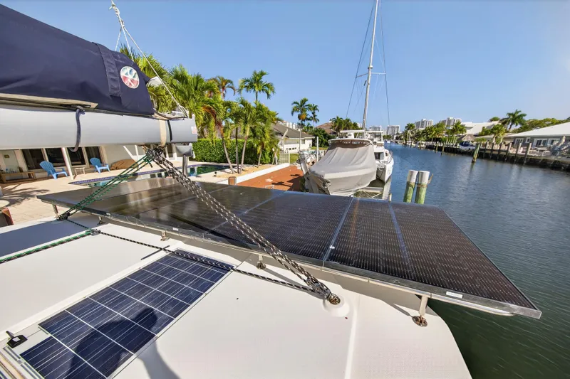  Yacht Photos Pics 2019 Leopard 45 catamaran with solar panels docked by a canal, surrounded by palm trees.