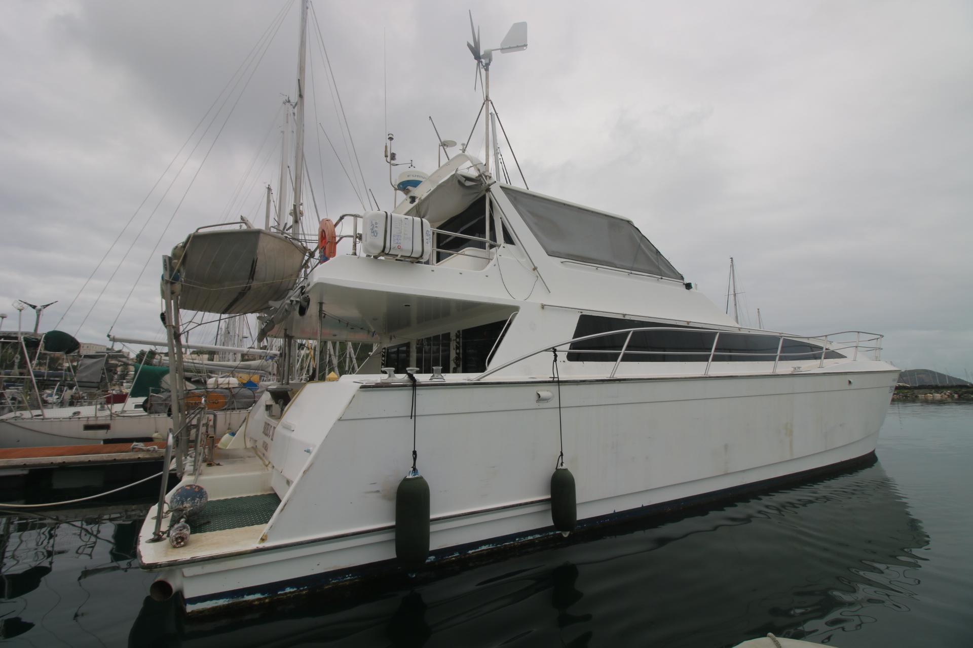 1991 Mitchell Powercat 58 yacht docked in a marina, overcast sky.