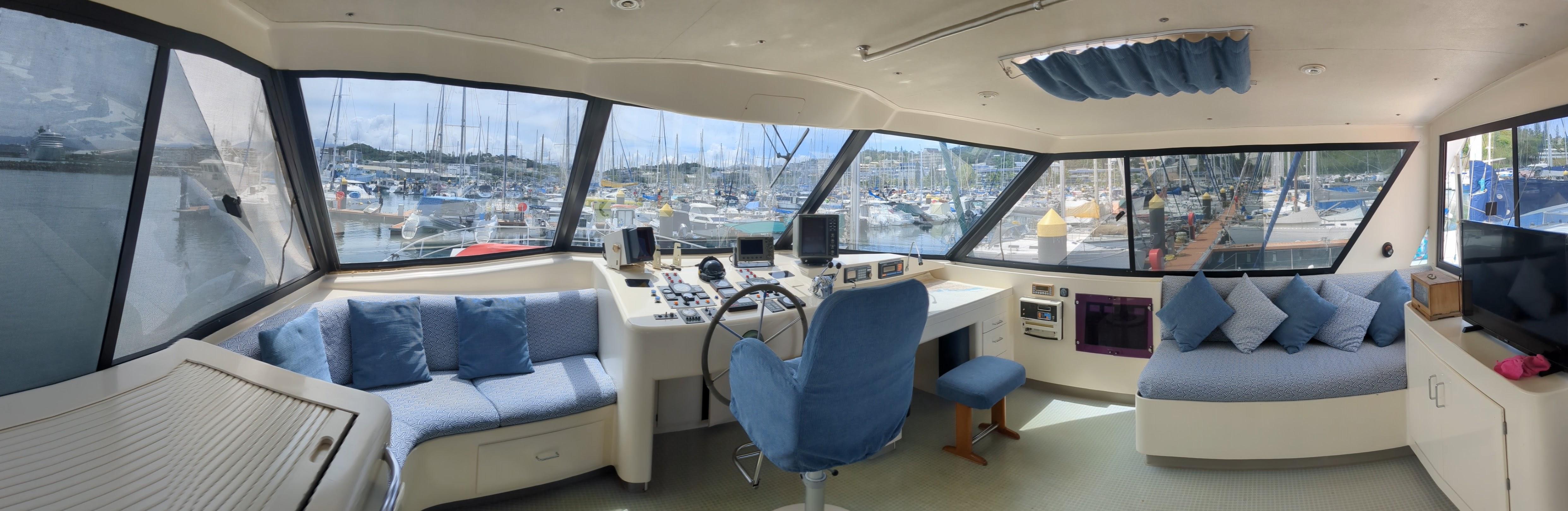 Interior of 1991 Mitchell Powercat 58 yacht with panoramic windows and blue seating.
