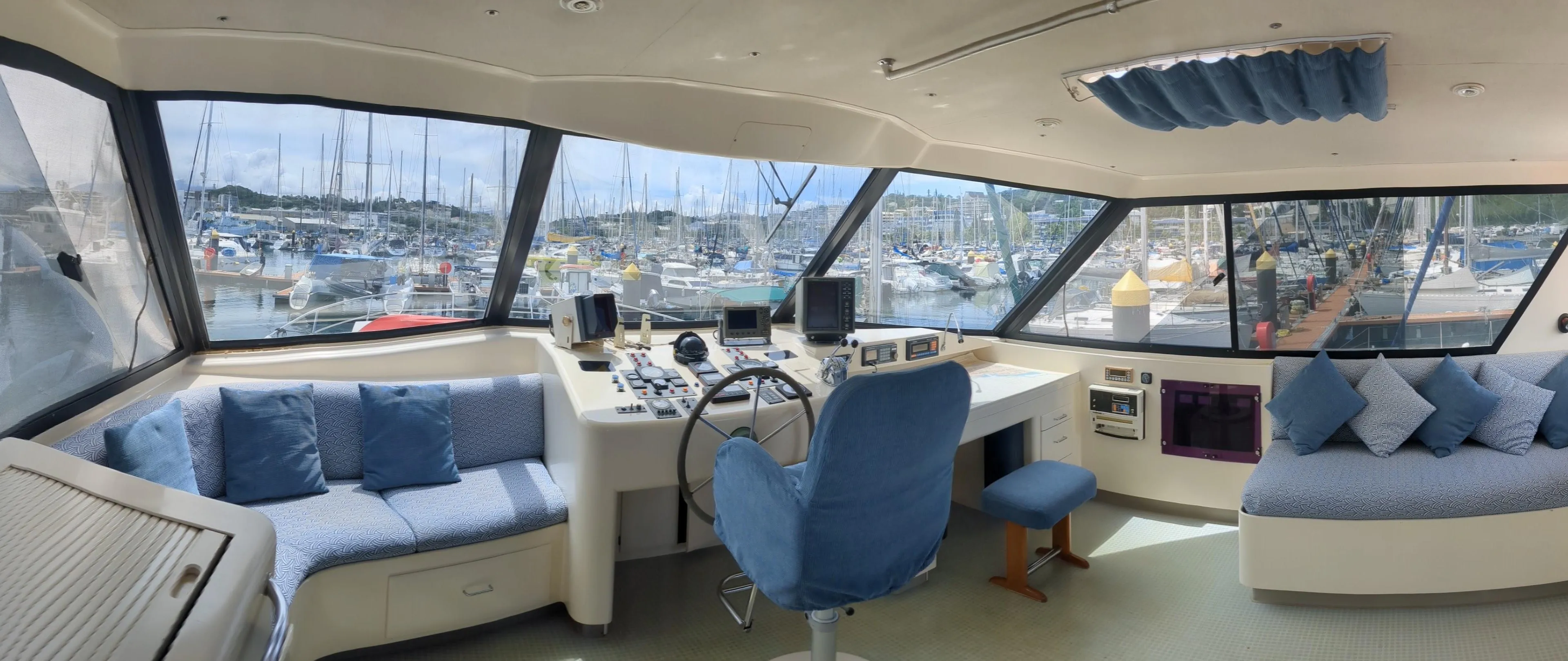 Interior of 1991 Mitchell Powercat 58 yacht with panoramic windows and blue seating.