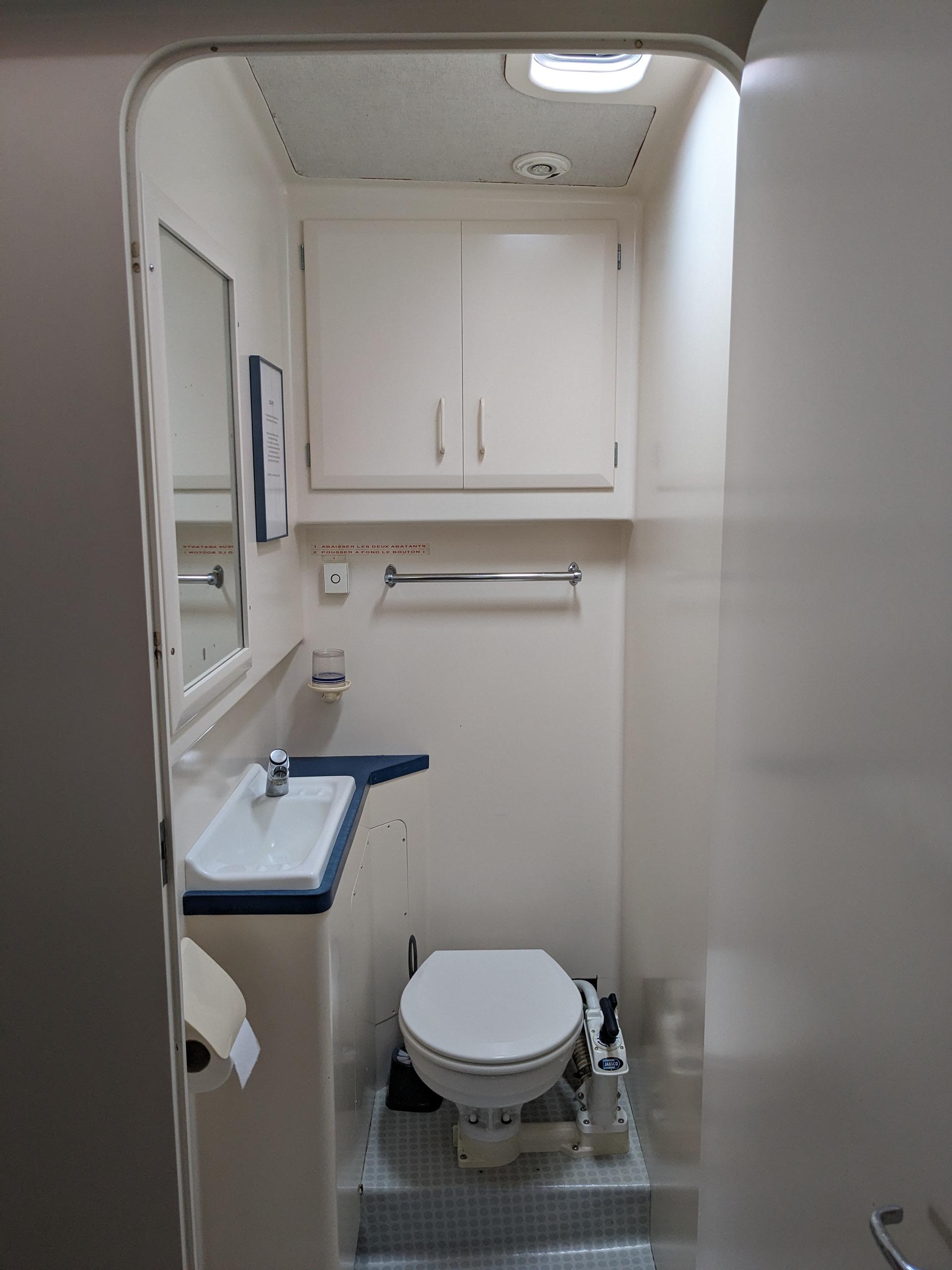 Bathroom interior of 1991 Mitchell Powercat 58, featuring toilet, sink, and storage cabinets.