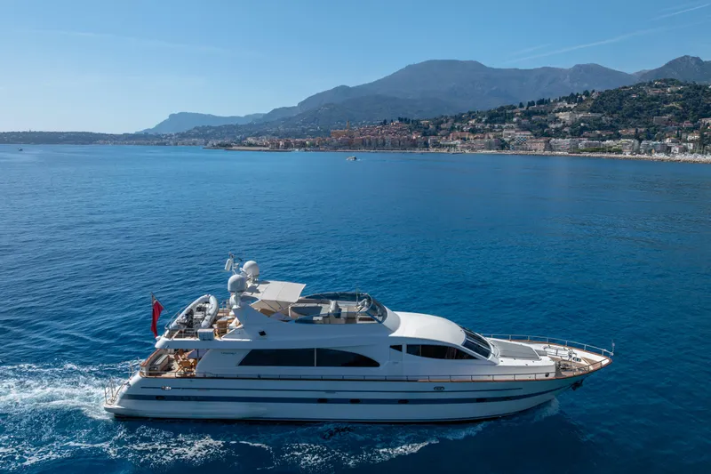  Yacht Photos Pics Falcon Yachts 86 (1999) cruising on blue waters near a scenic coastal town.