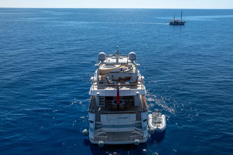  Yacht Photos Pics Falcon Yachts 86 (1999) cruising on open sea with a small boat nearby.