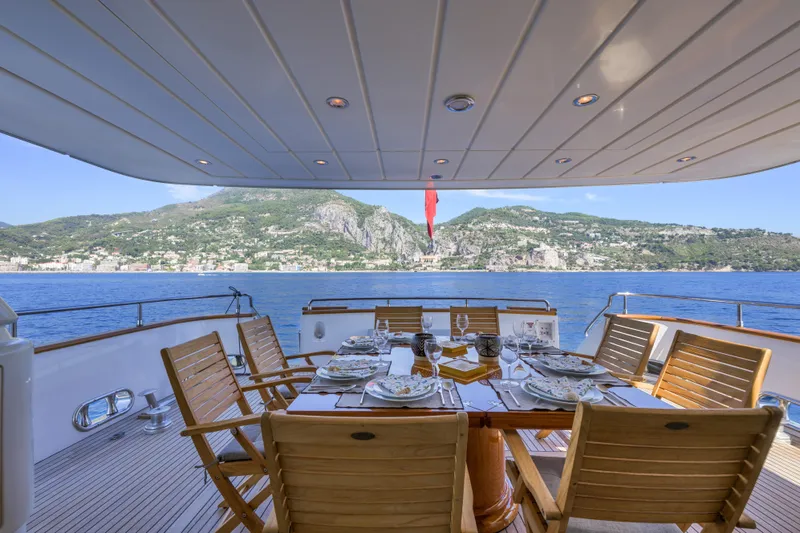  Yacht Photos Pics Luxurious dining setup on 1999 Falcon Yachts 86, overlooking scenic coastal view.
