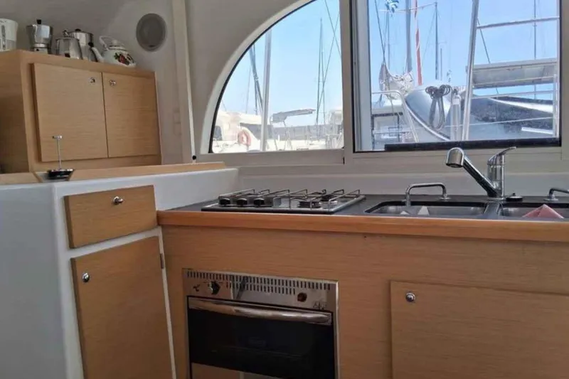 Sunny Days Yacht Photos Pics Compact kitchen in 2013 Lagoon 380 S2 yacht with stove, sink, and wooden cabinets.