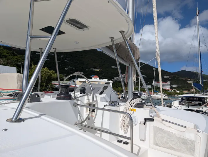 Southern Charm Yacht Photos Pics 2015 Lagoon 450 F catamaran helm with marina backdrop and clear skies.