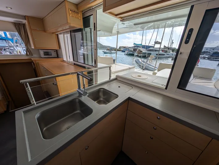 Southern Charm Yacht Photos Pics Interior view of 2015 Lagoon 450 F catamaran kitchen with dual sinks and marina backdrop.