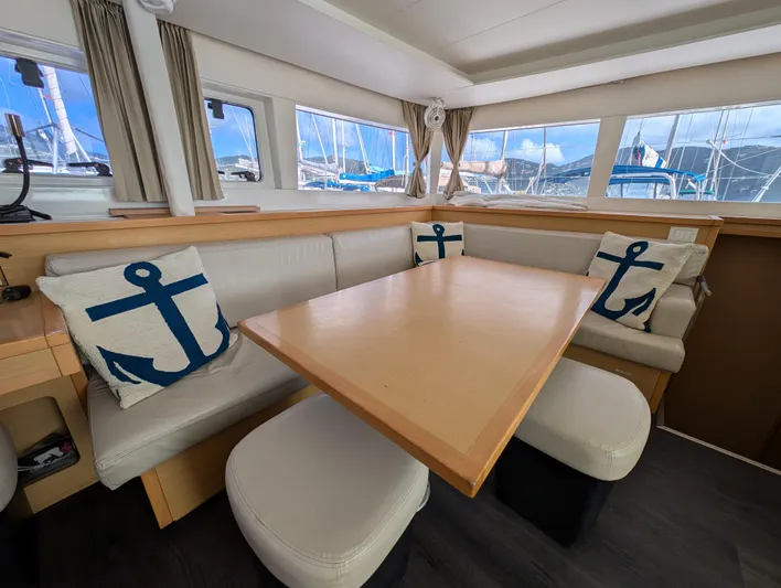 Southern Charm Yacht Photos Pics Interior of 2015 Lagoon 450 F catamaran with anchor-themed cushions and wooden table.