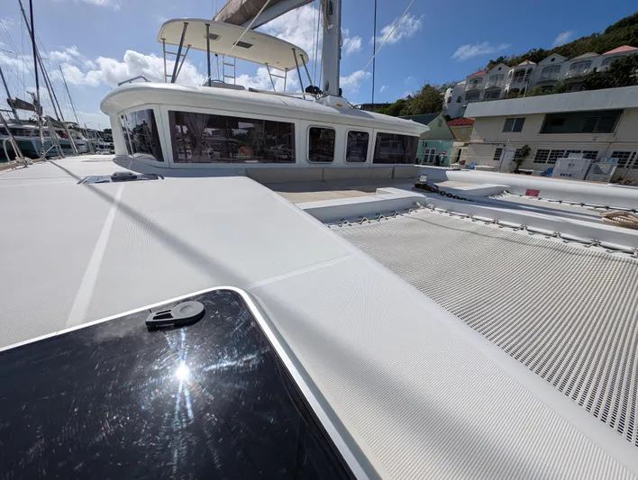 Southern Charm Yacht Photos Pics 2015 Lagoon 450 F catamaran deck with netting, docked under clear blue sky.
