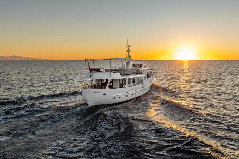 Sultana Yacht Photos Pics Vintage 1969 Feadship yacht cruising at sunset on open sea.