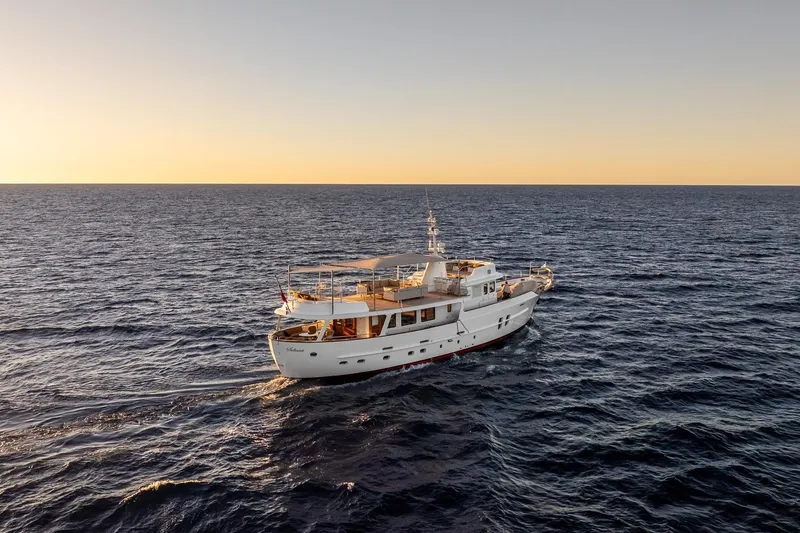 Sultana Yacht Photos Pics Vintage 1969 Feadship 25.8m yacht cruising at sunset on open sea.