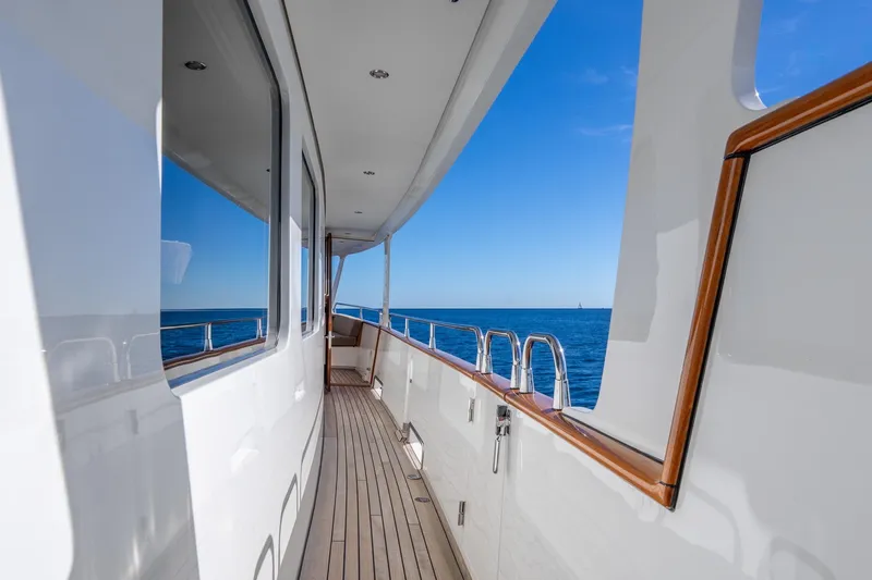 Sultana Yacht Photos Pics Side deck of 1969 Feadship 25.8m yacht with ocean view and wooden railings.