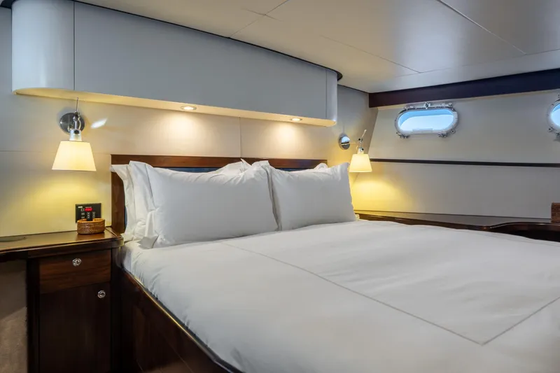 Sultana Yacht Photos Pics Luxurious cabin interior of 1969 Feadship 25.8m yacht with elegant bedding and ambient lighting.