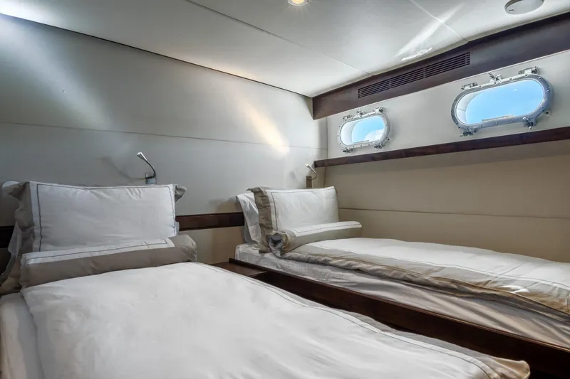 Sultana Yacht Photos Pics Luxurious twin cabin interior on a 1969 Feadship 25.8m yacht, featuring elegant bedding and porthole windows.