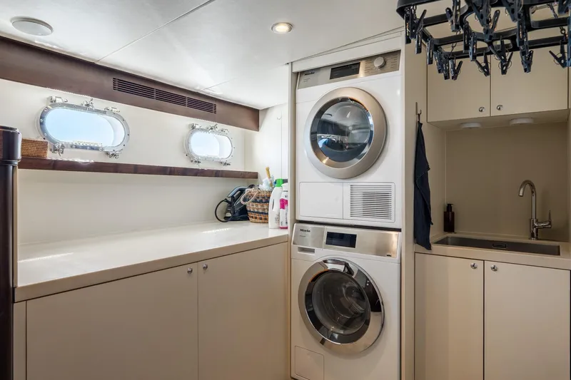 Sultana Yacht Photos Pics Laundry room on 1969 Feadship 25.8m yacht with washer, dryer, and porthole windows.