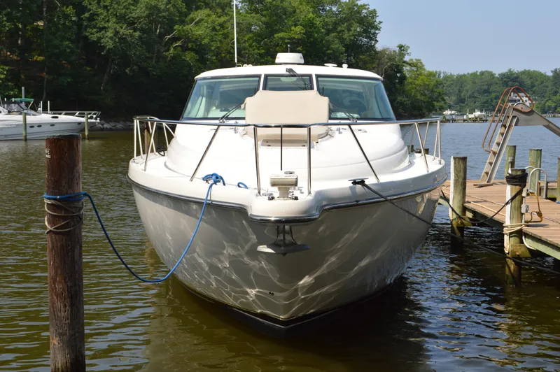 Lion Around Yacht Photos Pics 2006 Tiara Yachts 4300 Sovran docked on a calm lake with lush greenery.