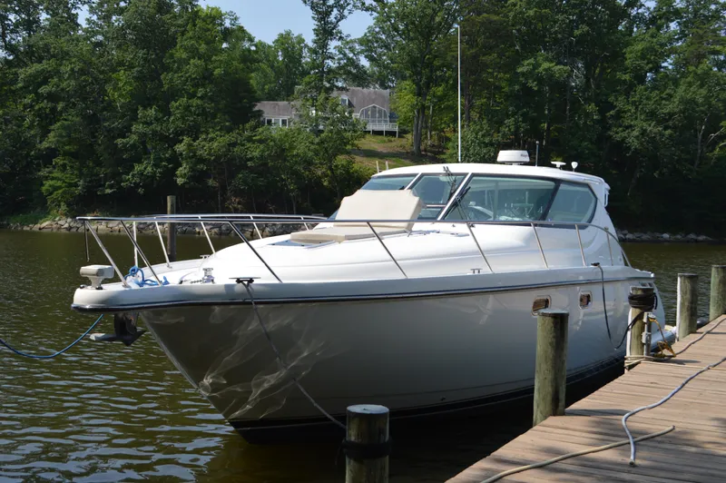 Lion Around Yacht Photos Pics 2006 Tiara Yachts 4300 Sovran docked by a serene lakeside with lush greenery.