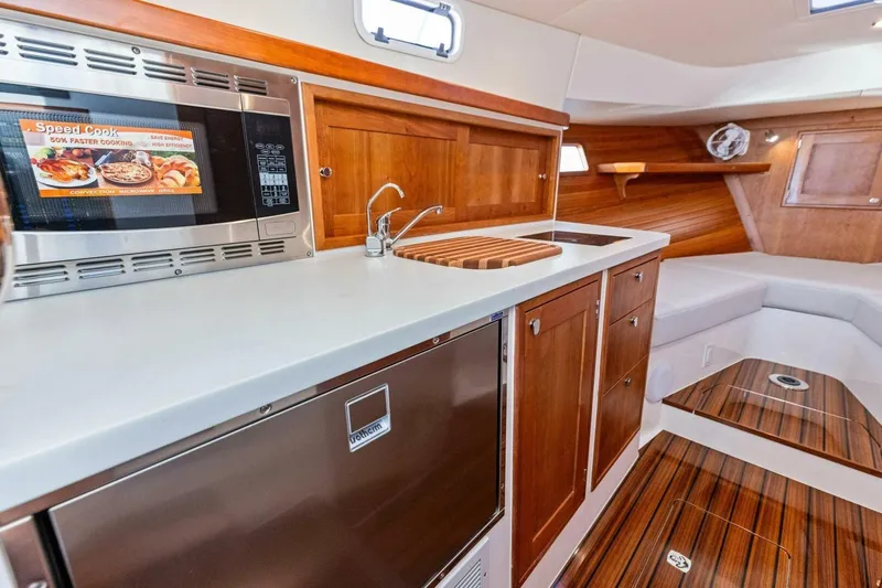  Yacht Photos Pics Modern MJM 35 yacht interior kitchen with microwave, sink, and wooden cabinetry, 2025 model.