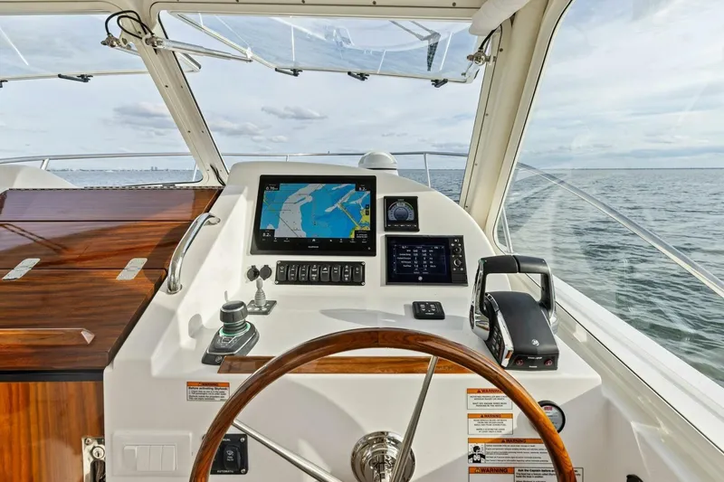  Yacht Photos Pics 2025 MJM 35 yacht helm with navigation screens and wooden steering wheel on open water.